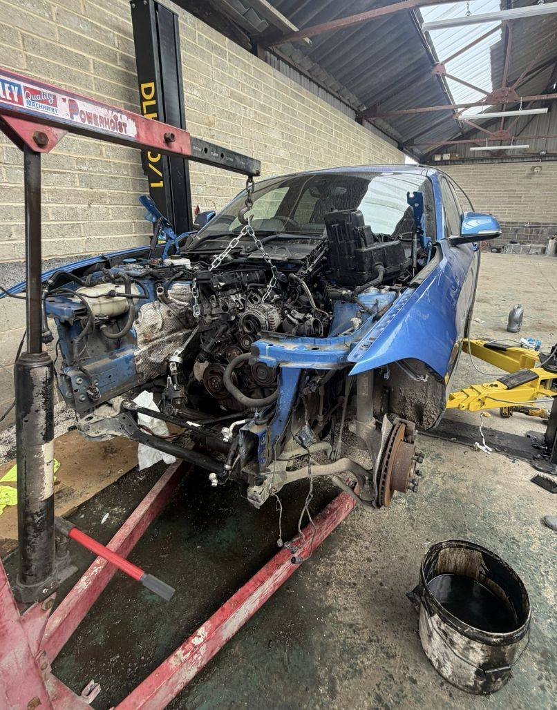 Car on the hoist with the engine being lifted out